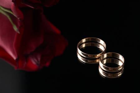75790613-close-up-van-twee-gouden-trouwringen-en-huwelijksboeket-van-rode-rozen-op-zwarte-achtergrond-gouden-